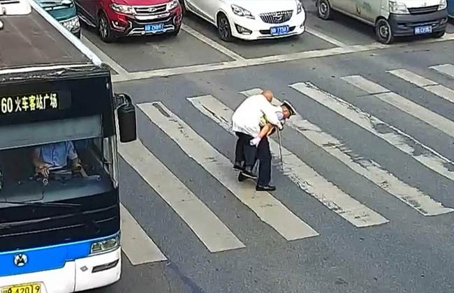 شرطي صيني يحمل رجلا مسنا على ظهره ويعبر به الشارع فيديو بوابة الأهرام
