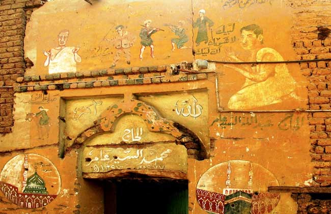 بوابة الأهرام تتابع رحلة الفنانين في تدوين رسومات الحج على جدران منازل الصعيد| صور